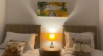 a bedroom with two beds with a picture on the wall at 2-Bed Barn Hot Tub & Pet Friendly near Muirkirk in Cumnock