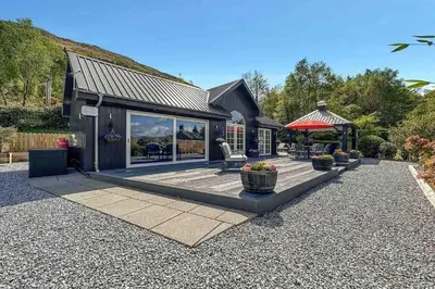 a house with a patio with a table and chairs at Little Fox Lodge Luxury Hideaway with Hot Tub Glencoe Near Fortwilliam in Glencoe