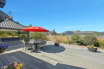 a table and chairs with a red umbrella on a deck at Little Fox Lodge Luxury Hideaway with Hot Tub Glencoe Near Fortwilliam in Glencoe