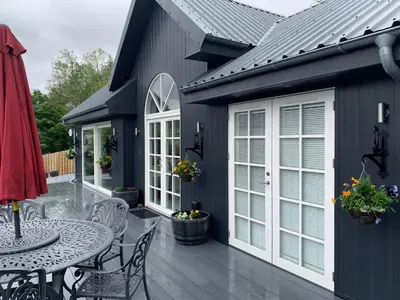 a black house with a patio with a table and chairs at Little Fox Lodge Luxury Hideaway with Hot Tub Glencoe Near Fortwilliam in Glencoe