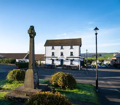 a building with a statue in front of a street at Black Bull Gartmore in Stirling