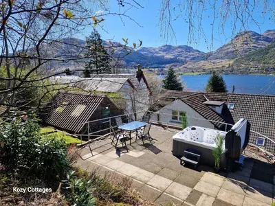 a patio with a table and a grill in a backyard at No 2 Planetree in Lochgoilhead