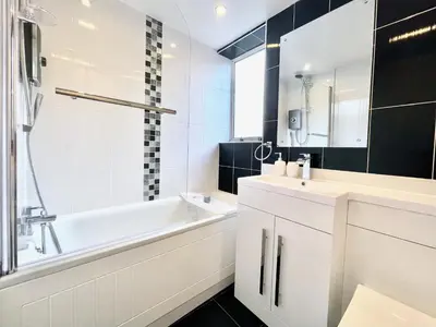 a bathroom with a white tub and a sink at Kingsbridge Apartment in Glasgow