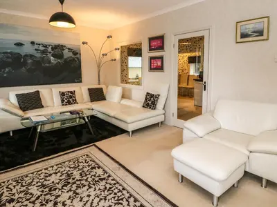 a living room with white couches and a table at Burnside House in Dalmally