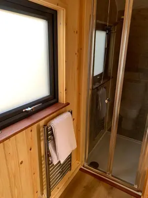 a bathroom with a shower and a window and a towel at The Stag Pod Farm Stay with Hot Tub Sleeps 2 in Galston