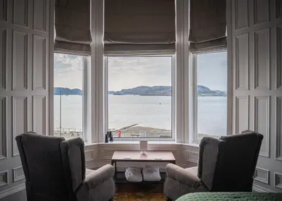 a room with two chairs and a large window at Witchwood House in Oban