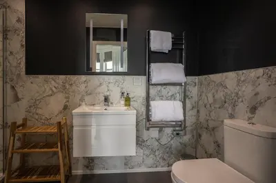 a bathroom with a sink and a toilet and a mirror at Witchwood House in Oban