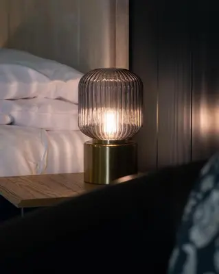 a lamp sitting on a table next to a bed at Witchwood House in Oban