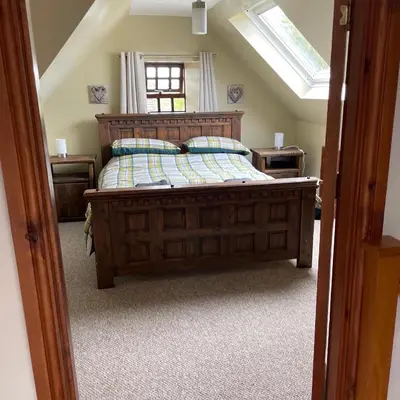 a bedroom with a large wooden bed with a window at Mawenyoupe in Lochgilphead