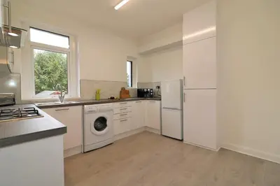 a kitchen with white cabinets and a washer and dryer at Macintosh lower in Bellshill