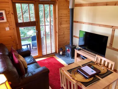 a living room with a couch and a television at Rashfield Sheilings - Quiet Riverside Lodges for Couples near Pucks Glen in Dunoon