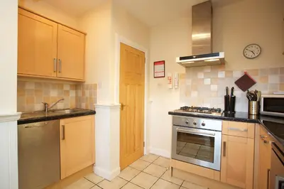 a kitchen with wooden cabinets and a stove top oven at Avonlea Self-Catering in Crieff
