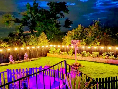 a garden with lights on a fence at night at The Green Monkey Lux Suite at The Grumpy Schnauzer B&B Private Hot Tub, Gym, Breakfast, Stunning! in New Monkland
