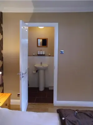 a bathroom with a sink and a toilet and a door at Ben Arthur's Bothy Luxury Flat in Arrochar