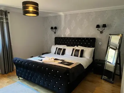 a bedroom with a bed with a black leather headboard at Ben Arthur's Bothy Luxury Flat in Arrochar