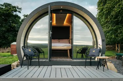 a gazebo with a bed and chairs on a deck at Cardross Estate Glamping Pods in Stirling