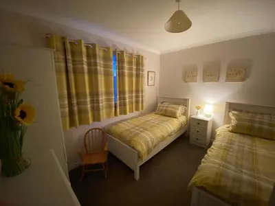 a bedroom with two beds and a chair and a window at Osborne Cottage in Southend