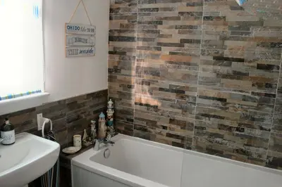 a bathroom with a bath tub and a sink at Osborne Cottage in Southend