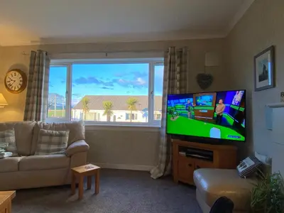 a living room with a flat screen tv and a couch at Osborne Cottage in Southend