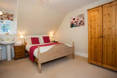 a bedroom with a bed with red pillows and a sink at Hawthornbank in Oban