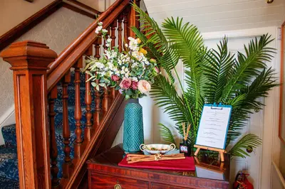a staircase with a blue vase with flowers on a table at Hawthornbank in Oban