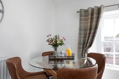 a dining room with a glass table and chairs at Stableyard Apartment: Drumlanrig Castle in Thornhill