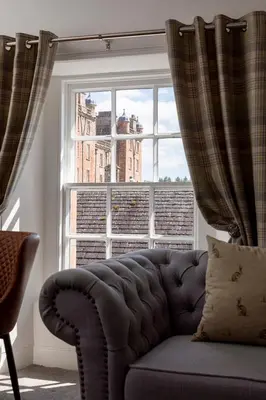 a couch sitting in front of a large window at Stableyard Apartment: Drumlanrig Castle in Thornhill