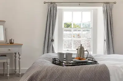 a bed with a tray of food on it with a window at Stableyard Apartment: Drumlanrig Castle in Thornhill