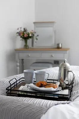 a tray with breakfast foods and two cups on a bed at Stableyard Apartment: Drumlanrig Castle in Thornhill