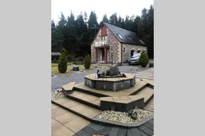 a building with a fountain in a parking lot at Private Coach house in gated residence in Stirling