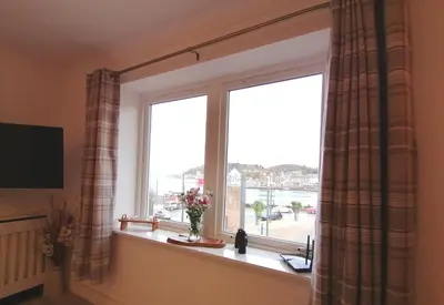 a window with a vase of flowers on a window sill at Seaside Apartment in Oban