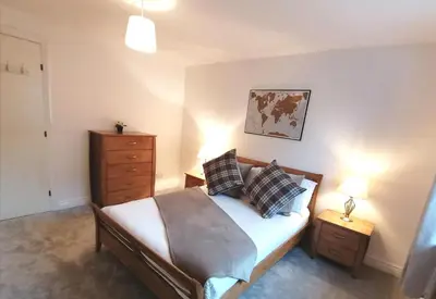 a bedroom with a bed with pillows and a dresser at Seaside Apartment in Oban