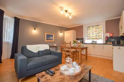 a living room with a couch and a table at The Gallery Apartment - Spacious, Town Centre, Walkable to Ferry Terminal, in Oban