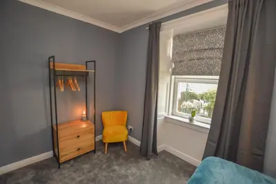 a bedroom with a chair and a window at The Gallery Apartment - Spacious, Town Centre, Walkable to Ferry Terminal, in Oban