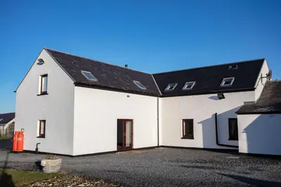 a white house with a black roof at Kentraw Farmhouse Luxury Self Catering in Bruichladdich