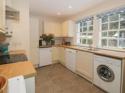 a kitchen with white cabinets and a washer and dryer at Maisie's Cottage in Dunblane