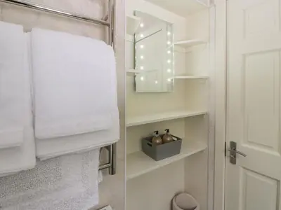a bathroom with white towels and a mirror at Maisie's Cottage in Dunblane