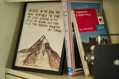 a shelf with books and a picture of a mountain at An Airigh in Cairndow