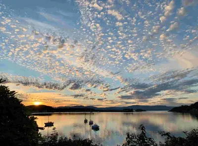 a cloudy sky over a lake with boats in it at The Manor House in Oban