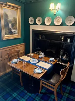 a wooden table with plates on it in a room with a fireplace at The Manor House in Oban
