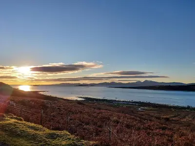 a sunset over a body of water with the sun setting at Ar Deireadh in Tayvallich