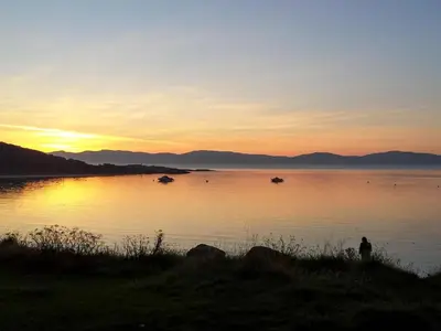 a sunset on a lake with boats in the water at Ar Deireadh in Tayvallich