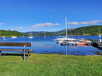a bench sitting next to a marina with boats in the water at Ar Deireadh in Tayvallich
