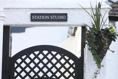 a sign that says station studio on a building with a plant at Garden Studio in Biggar in Biggar