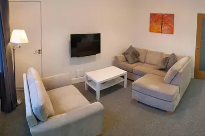 a living room with two couches and a flat screen tv at Glenfinnan - Two Bedroom Apartment in Fife