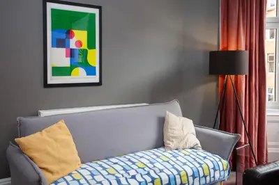 a living room with a gray couch with pillows at Modern, Light-filled and Sleek West End Apartment in Glasgow