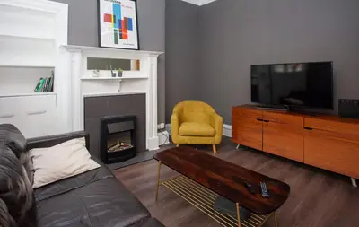 a living room with a couch and a tv and a fireplace at Modern, Light-filled and Sleek West End Apartment in Glasgow