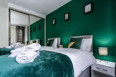 a green bedroom with two beds and a mirror at Cheerful 2 Bedroom Homely Apartment, Sleeps 4 Guest Comfy, 1x Double Bed, 2x Single Beds, Free Parking, Free WiFi, Suitable For Business, Leisure Guest, Contractors, QE Hospital, Glasgow, Near Airport & City Centre, Perfect For Common Wealth Games 2026 in Glasgow