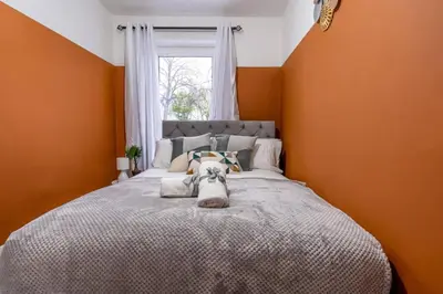 a dog laying on a bed in a bedroom at Cheerful 2 Bedroom Homely Apartment, Sleeps 4 Guest Comfy, 1x Double Bed, 2x Single Beds, Free Parking, Free WiFi, Suitable For Business, Leisure Guest, Contractors, QE Hospital, Glasgow, Near Airport & City Centre, Perfect For Common Wealth Games 2026 in Glasgow