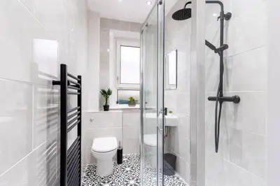 a bathroom with a toilet and a glass shower at Cheerful 2 Bedroom Homely Apartment, Sleeps 4 Guest Comfy, 1x Double Bed, 2x Single Beds, Free Parking, Free WiFi, Suitable For Business, Leisure Guest, Contractors, QE Hospital, Glasgow, Near Airport & City Centre, Perfect For Common Wealth Games 2026 in Glasgow